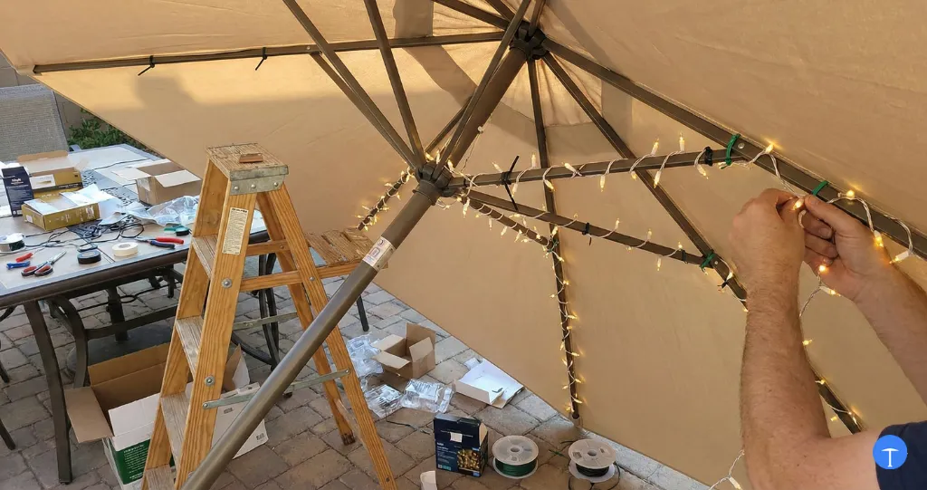 How to install lights on patio umbrella showing string lights being zip-tied to umbrella ribs